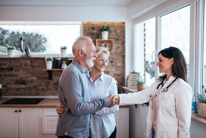 Senior couple greeting a female doctor.