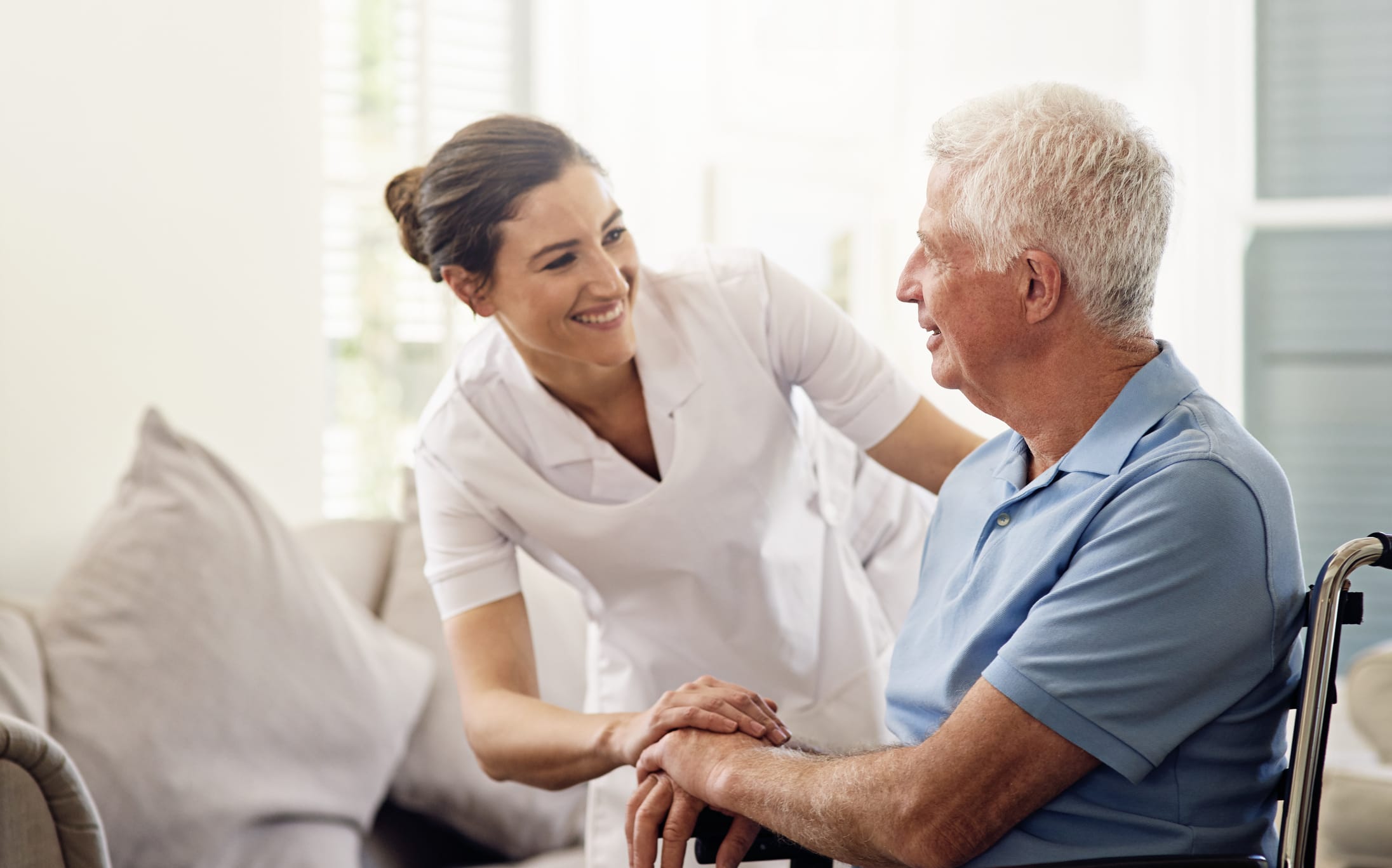 A caregiver comforts a senior sitting in a chair