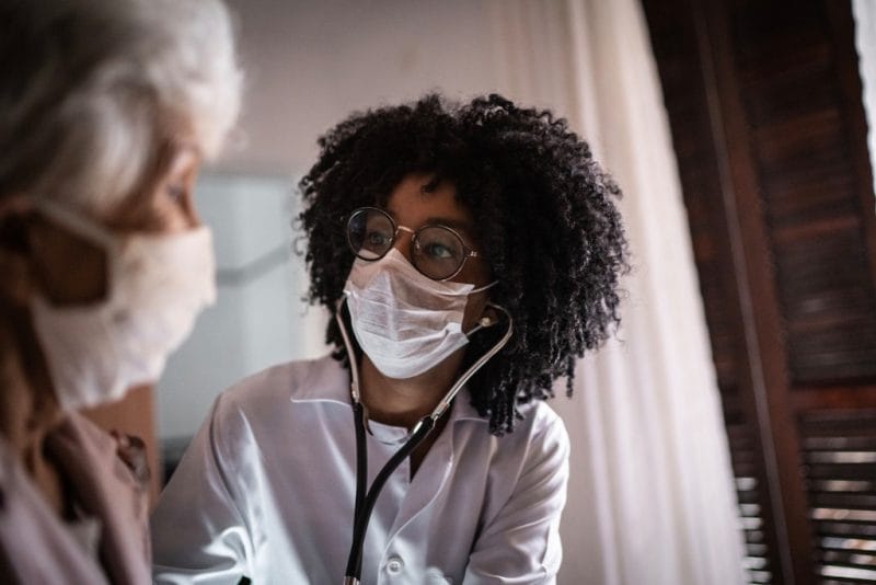 A caregiver checks a senior's vitals using a stethoscope.