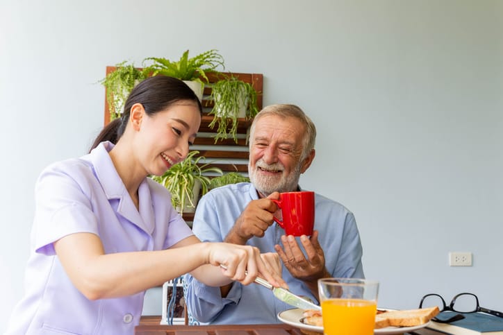 Nurse assists a senior man during breakfast