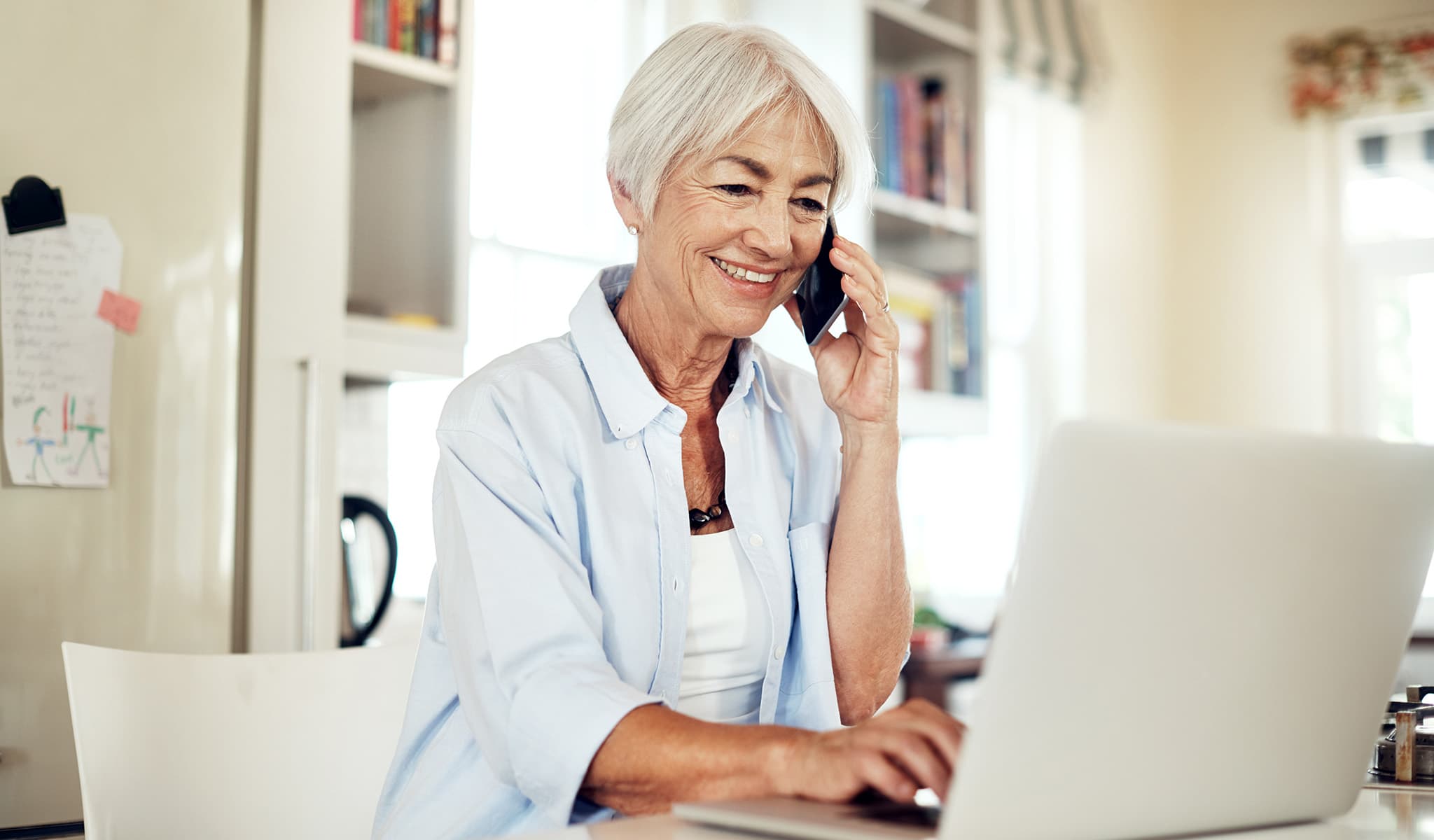 Older woman on phone while looking at computer