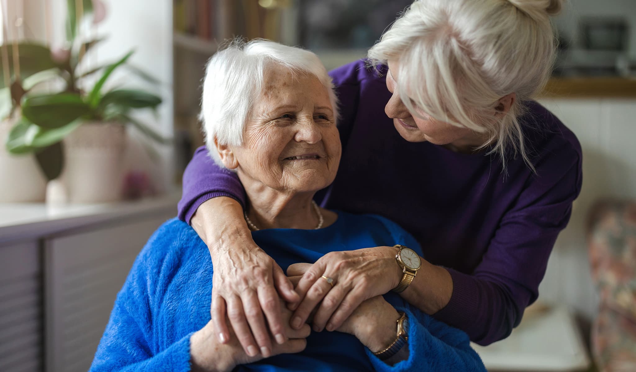 Senior woman being embraced by a friend or relative