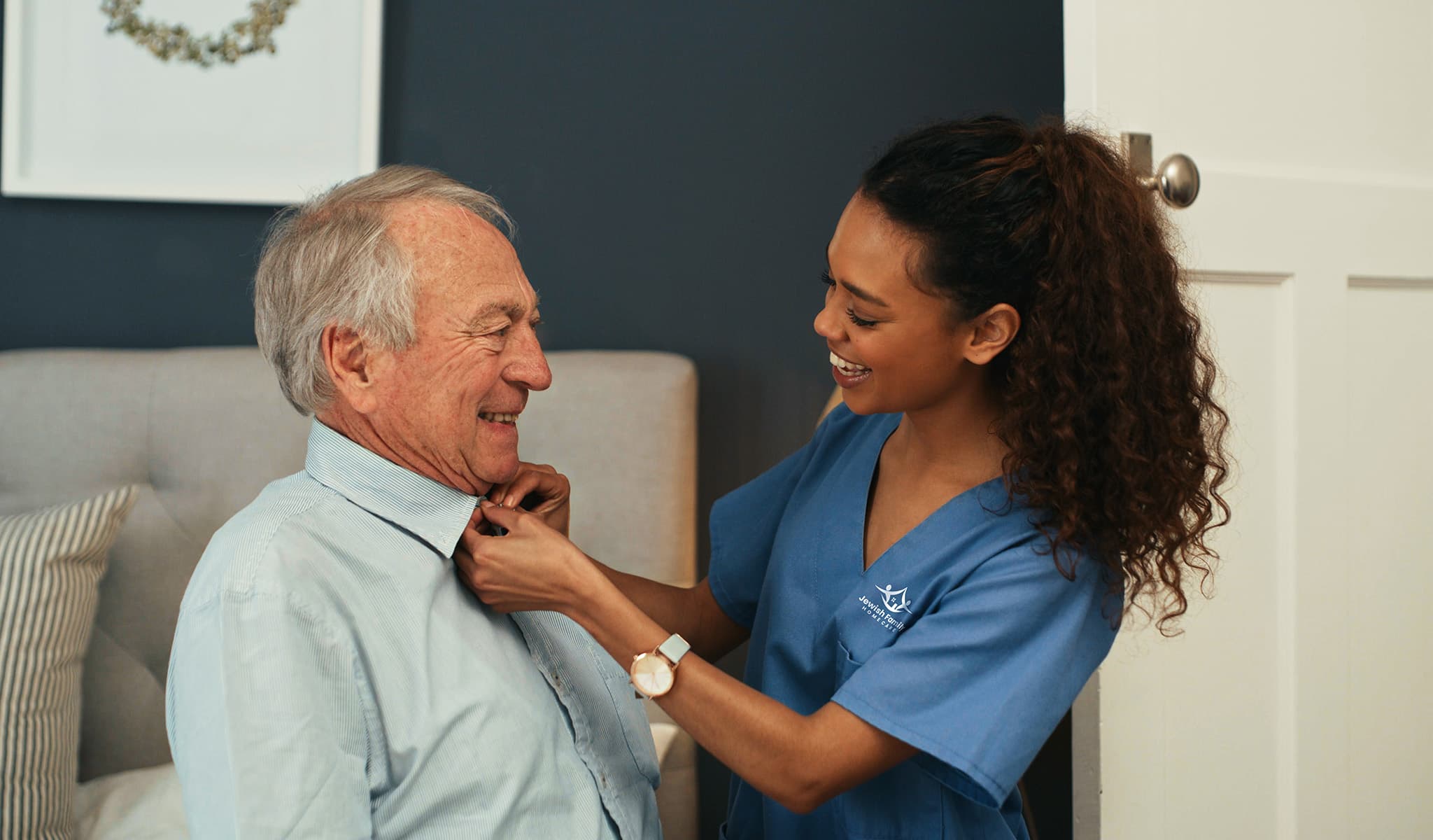 Caregiver helping senior button his shirt