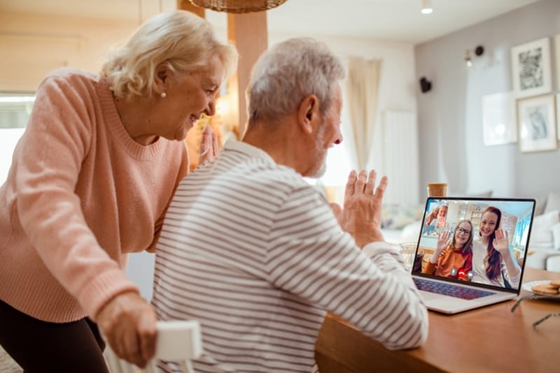 A senior couple FaceTime with their daughter and granddaughter who live far away, emphasizing the important role of home care in ensuring senior loved ones have the support they need when family members can’t be there to help.