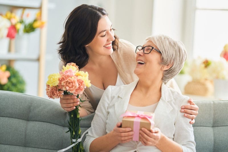 A daughter brings her senior mother a present and flowers to make Mom center stage this Mother’s Day.