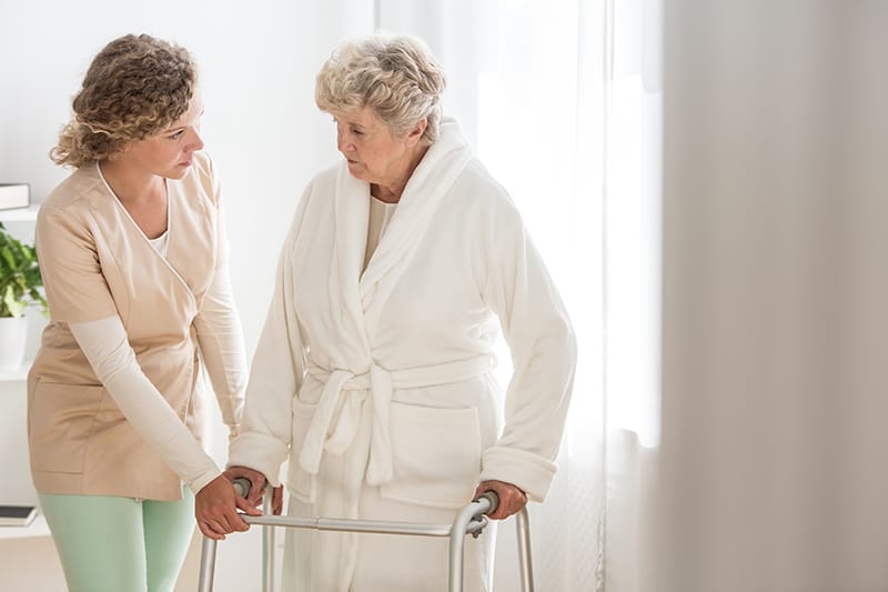 A caregiver helps a senior woman prepare for a bath, a key step in helping overcome bathing challenges in older adults.