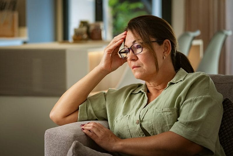 A woman experiencing caregiver stress and burnout stares off into the distance wondering how to find balance.