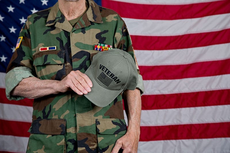 A veteran stands in front of the American flag, a symbol of how important helping veterans is once they return home.